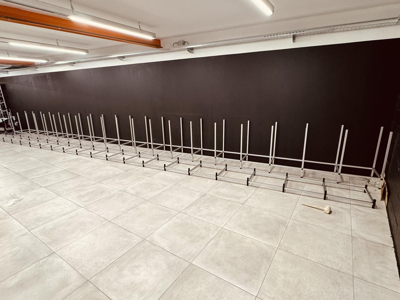 De zwarte wand met de gemonteerde dragers voor de stellingen, nog leeg